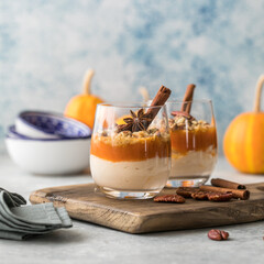 Autumn trifle dessert. Layered pumpkin parfait , pecan nut dessert in a glass, with autumn decorations.