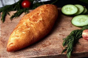 patty on a wooden board with cucumber, herbs, tomatoes and a napkin on a black background