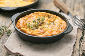 Frittata with mushrooms in a pan on wooden background. Fritata is an Italian breakfast dish.