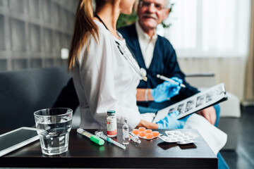 In the foreground, the focus is on drugs, in the background, a blurred nurse advising her patient