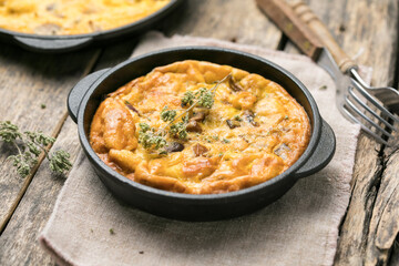 Frittata with mushrooms in a pan on wooden background. Fritata is an Italian breakfast dish.