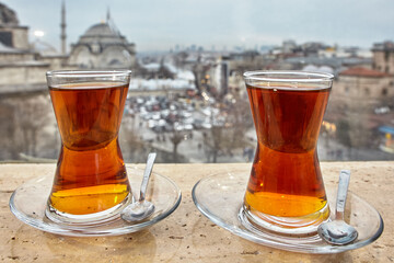 Turkish tea glasses with saucers and spoons against backdrop of cityscape of Istanbul.