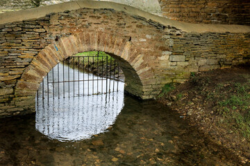 View of the archway of the Bath Bridge with the gate on the river with reflection