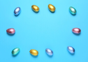 Frame made of sweet chocolate eggs on color background