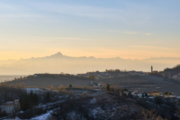 Panoramic view of the Langhe vineyard hills at sunset with the Alps mountain range and the Monviso peak in the background in winter, Monforte d'Alba, Cuneo, Piedmont, Italy