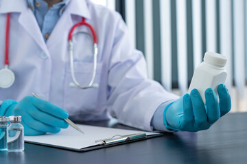 A doctor in blue gloves or a pharmacist with a bottle of medicine in hand is writing a patient treatment guide, patient dispensing and treatment ideas.