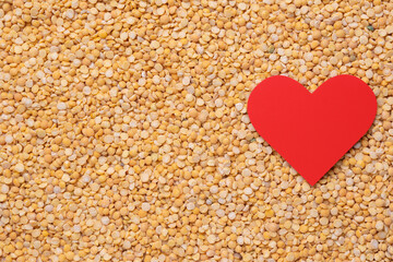 Red heart on a background of dry peas. Copy-space
