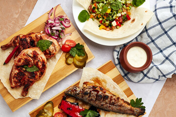 grilled fish and meat, salad and milk on the table with a white towel