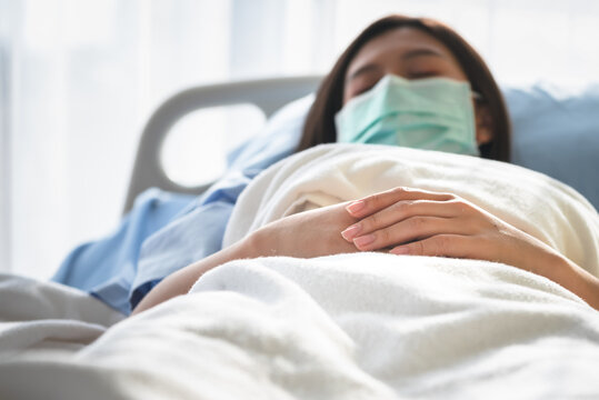 Blurred soft images of Asian woman patients wear a surgical mask Prevent the spread of germs, lying in patient's bed with alone, to people health care and Covid-19 infection concept.