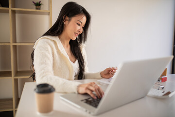 Fototapeta premium Portrait of Young woman using credit card,smartphone and laptop computer at home. Online shopping, e-commerce, internet banking, spending money, working from home concept