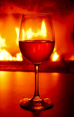 Close-up of a glass of white wine in the backlight of a burning fireplace.