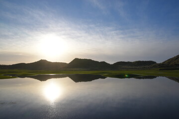 the sand dunes of ynyslas wales reflected in the flooded waters  next to the road 