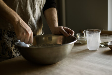 Male hands kneading batter in bowl