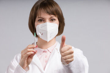 female doctor or nurse with syringe pulled up with a vaccination serum shows thumbs up