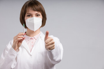 female doctor or nurse with syringe pulled up with a vaccination serum shows thumbs up