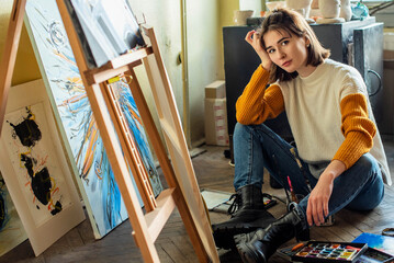 Beautiful woman painting. Girl in Painting Studio. Talented Female Artist Working on a Modern Abstract Oil Painting, Gesturing with Broad Strokes Using Paint Brush. Dark Creative Studio