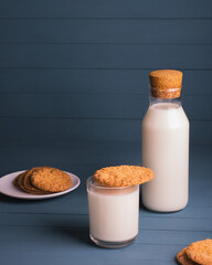 Plate with chip cookies and glass  and bottle of milk on blue wooden background