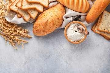Various crispy breads and buns, wheat flour and ears on light gray concrete background table. Top view flat lay with copy space