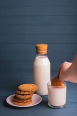 Plate with chip cookies and glass  and bottle of milk on blue wooden background