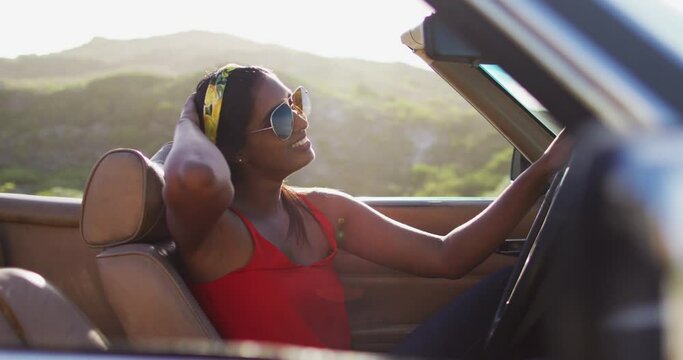Portrait of african american woman sitting in the convertible car on road