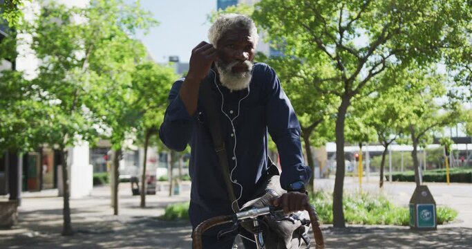 African American Senior Man Sitting On Bicycle Wearing Earphones On The Road