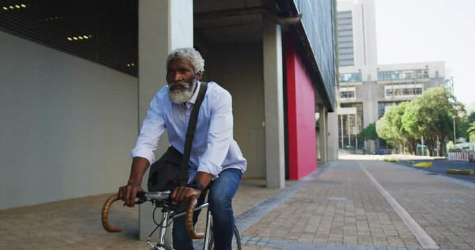 African american senior man riding a bicycle in corporate park
