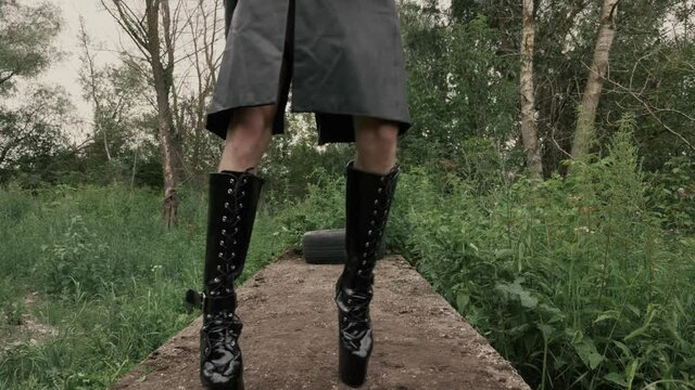 Gay guy in a female wig tries to walk like a girl in high heels and to pose like a woman