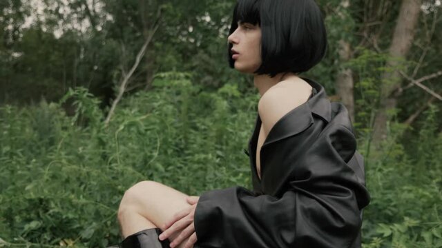Cute transvestite guy in black wig playfully flirts smiling and looking forward