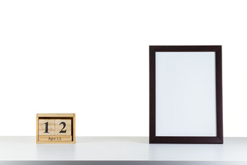 Wooden calendar 12 april with frame for photo on white table and background
