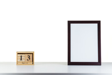 Wooden calendar 13 april with frame for photo on white table and background