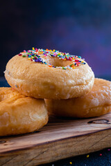 glazed donuts on wooden base with dark background