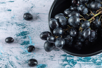 Dark fresh grape in bowl on a colorful background