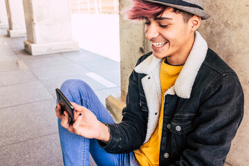 Teenager young man with style and colorful violet hair and hat use smartphone to connect and enjoy...