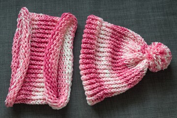 Close up colorful yarn texture of pink white hat and scarf. Shallow depth of focus. Knitting and crochet, craft work concept. Winter clothes, kids fashion. Color combination for styling and dressing.