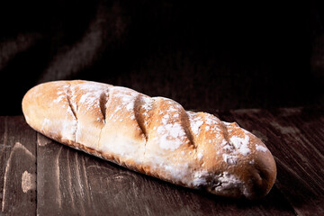 Several loaves of bread wheat, baguette in a wicker basket on a black background