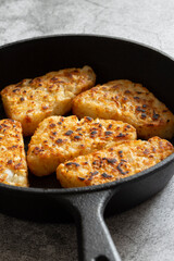 Hash browns cooked in a cast iron frying pan.  Concrete background