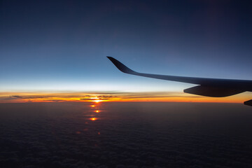 Fototapeta na wymiar Jet in the sky at awesome sunrise. Plane wing above clouds. Beautiful view from airplane window. Morning colorful sky with sun light. Aviation concept. Flight concept. Aerial view of clear sky.