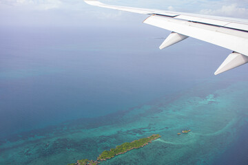 Beautiful view from airplane window. Indian ocean and african island from the plane. Airplane wing and aerial view of scenic lagoon. Aviation travel. Africa landscape from airplane. Tropical vacations