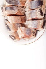 Salted herring on oval plate on a light background . Marinated sliced fish. Traditional russian appetizer
