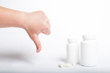 Hand showing thumb down to medicines. Pills and thumb down.