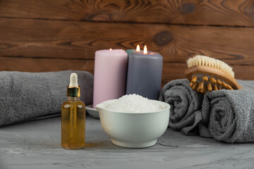 Herbal therapy, traditional medicine and homeopathy concept. Towel with salt, herbs, massage brush, candles and bottle natural organic oil essence serum. Set for spa, massage and aromatherapy 