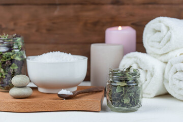 Herbal therapy, traditional medicine and homeopathy concept. Towel with salt, herbs and aroma candles. Set for spa, massage and aromatherapy