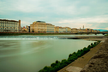 Fototapeta premium Long exposure river looking at colorful bright buildings day trip in Florence, Italy, Arno River