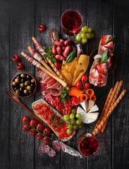 Antipasti, a traditional Italian snack on a dark wooden table. Sliced meat. Top view