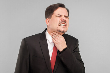 Bad feelings concept. Businessman have neck pain. Indoor, studio shot, isolated on gray background