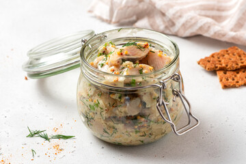 Pickled herring in a glass jar. Senapssill. Pickled herring with mustard, vinegar, onion, oil, dill, and sour cream. Scandinavian cuisine.