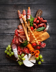 Antipasti, a traditional Italian snack on a dark wooden table. Sliced meat. Top view. - 416102309