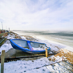 Blue boat on the shore of the frozen sea