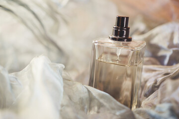 Bottle with perfume on an airy fabric close-up.