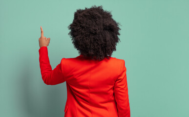  standing and pointing to object on copy space, rear view